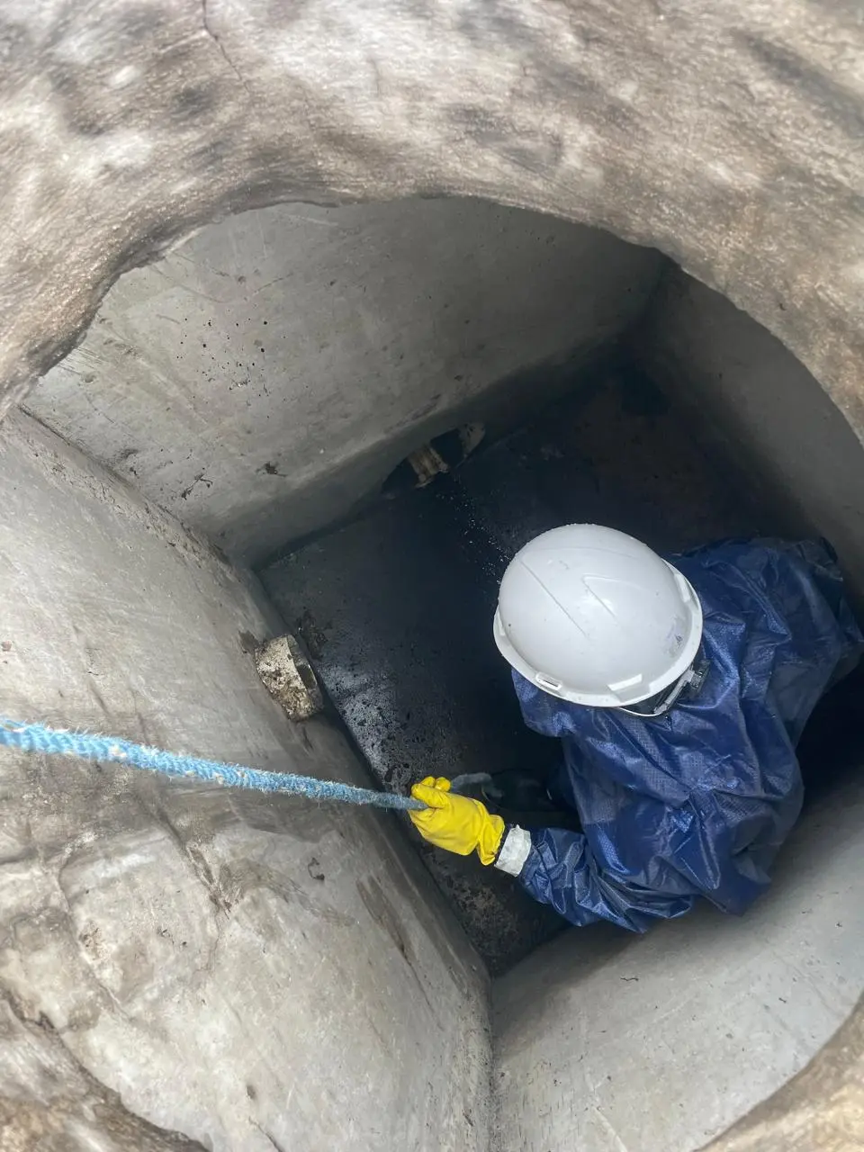 Técnico con casco y traje de protección haciendo limpieza de pozos sépticos en quito