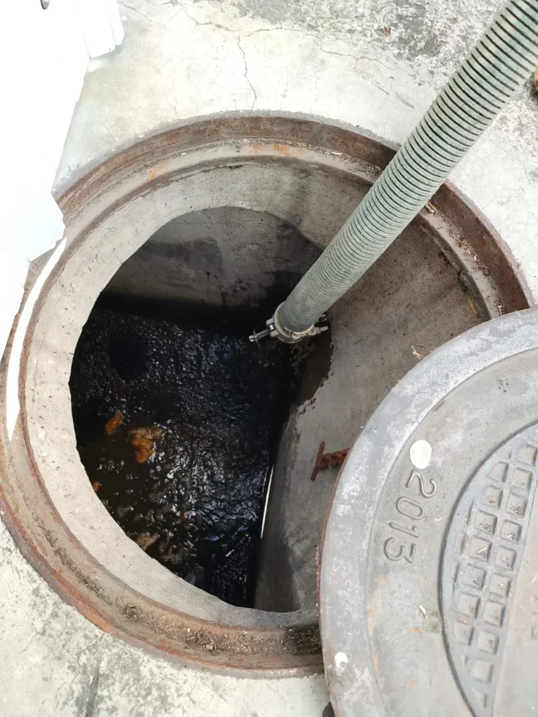 Manguera de succión extrayendo aguas residuales de un pozo séptico
