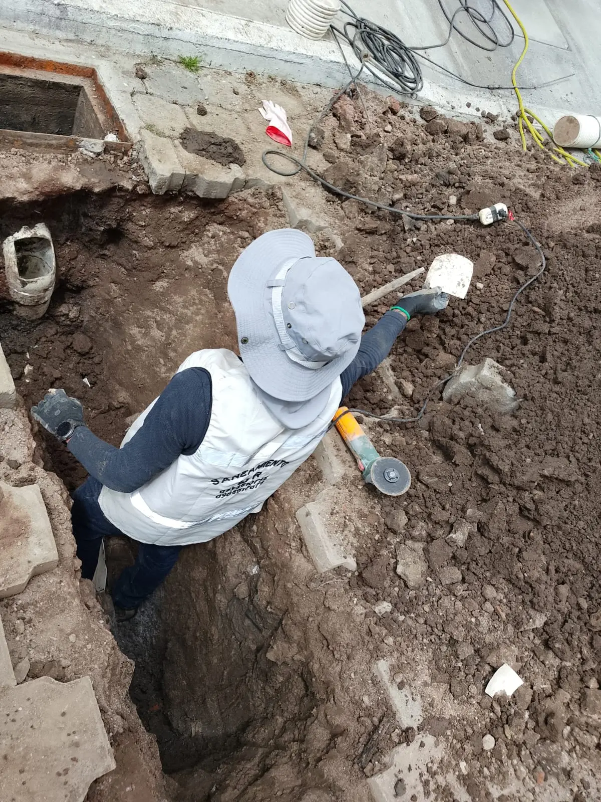 Técnico excavando junto a un pozo séptico para descubrir la tubería de descarga