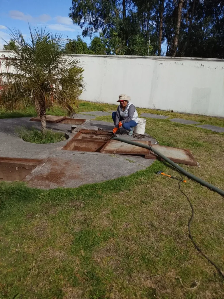 Técnica colocando la manguera de succión en un pozo séptico ubicado en un jardín